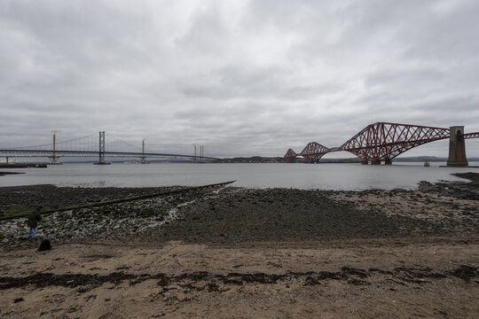 Edinburgh, United Kingdom - 07 December 2016: View of the iconic red Forth Bridge piercing the grey sky, a stark contrast to the pale Firth of Forth waters.