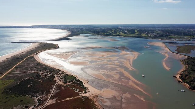 Aerial drone view over Alvor estuary in Algarve, Portugal, showing tidal sandbanks, coastal wetlands, and reflective waters under sunlight. Concept of natural beauty and ecological diversity