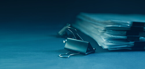 Pile of documents and binder clips on dark blue background.