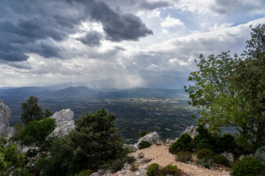 Storm, dark clouds, impending rain in the mountainous regions of Sardinia: the area around Supramonte di Baunei, Ardali. In the foreground, rocks and trees