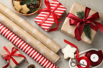 Festive packaging. Gift boxes, wrapping paper, gingerbread cookies, ribbon and scissors on light textured table, flat lay. Merry Christmas and Happy New Year