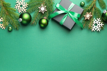 Beautiful Christmas composition with gift and decor on green background, flat lay. Space for text