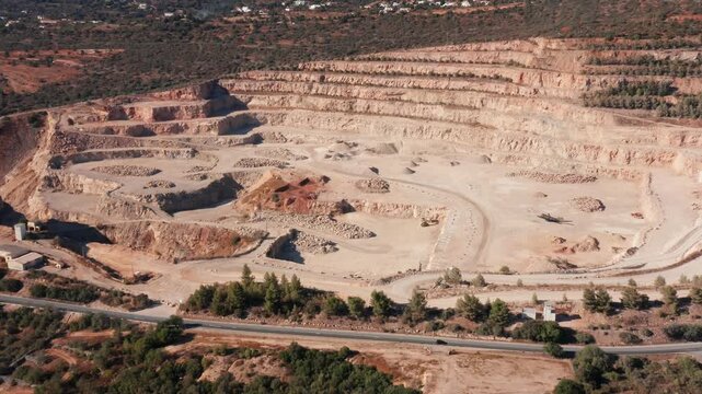 conveyor corridors and stockpiles visible, aerial vista of material flow with processing buildings, supply roads and loading zones, industrial rhythm and dust prone surfaces under warm light