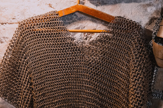 Chainmail armor vest made of metal rings, displaying ancient protection and historical craftsmanship on a wooden hanger