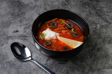 Red Tomato Soup In Black Bowl With Olive Slices, Cream