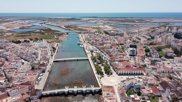 aerial estuary view tavira portugal with visible salterns and tidal channels, nature documentary shot showing marshes, mudflats, wildlife habitat and long coastal approach to sea