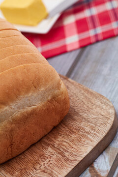 A freshly baked loaf of Jamaican sliced hard dough bread on a cutting board with a stick of butter and a knife