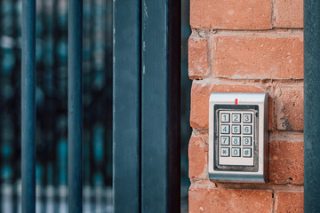 Keypad access control system mounted on a red brick wall, protecting home or business entrance with security code