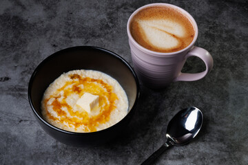 Creamy Oatmeal Breakfast Bowl With Butter, Syrup, And A Cup Of Coffee In A Pink Mug