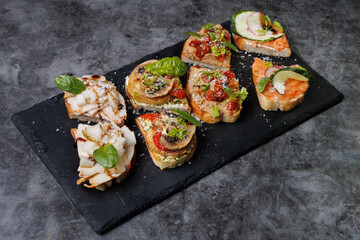 Assorted Gourmet Canaps On Black Slate Board for Elegant Party Platter and Tasting Experience