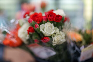 Blossoming bouquet of red and white flowers wrapped in clear plastic sits awaiting its lucky recipient