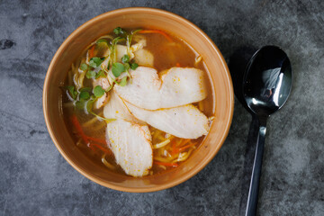 Wholesome Chicken Noodle Soup in Ceramic Bowl With Fresh Greens and Carrot Garnish