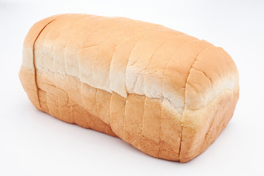 A small, freshly baked loaf of Jamaican sliced hard dough bread isolated on a white background