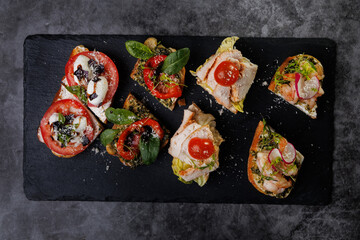 Assorted Crostini and Canap s on Slate Board Featuring Tomato, Cheese, Basil, and Seafood Toppings