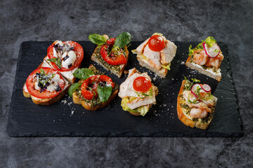 Assorted Crostini and Canap s on Slate Board Featuring Tomato, Cheese, Basil, and Seafood Toppings