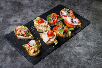 Assorted Crostini and Canap s on Slate Board Featuring Tomato, Cheese, Basil, and Seafood Toppings