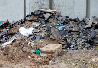 Pile of roofing felt waste near the wall of a building., waste separation, garbage, disposal of hazardous waste on the construction site