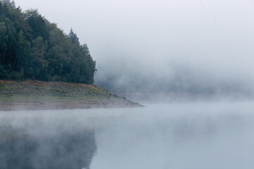 Obraz premium Misty Morning Atmosphere Over a Calm Lake