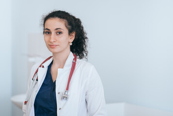 A confident doctor with a stethoscope stands in a clinic, ready to provide care with a warm smile.