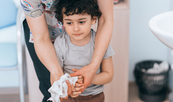 Close-up of adult helping child wash hands under a stream of water, focusing on hygiene and bonding.