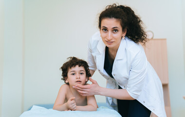 A pensive child sits on an examination table while a doctor observes nearby, preparing for the next step in the medical consultation.