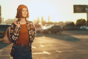 Woman walking in urban street at golden hour glow with shopping bag, candid lifestyle portrait...
