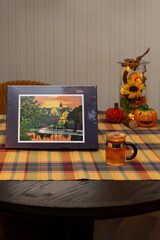 A 500 piece jigsaw puzzle lies on the table in an autumnally decorated apartment. It shows an illustration of the town of Brilon in the Sauerland region. A hot cup of tea symbolizes a cozy pastime.