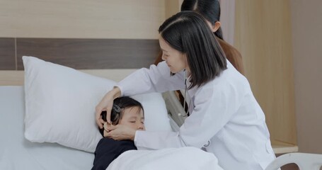 Hospital concept of 4k Resolution. The doctor is placing a hearing aid on the girl’s ear and testing her hearing in the patient room.