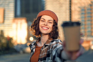 Fototapeta premium Woman smile coffee city beanie urban portrait outdoors capturing authenticity and candid lifestyle in golden hour glow, mindful living and emotional storytelling with joyful urban warmth.