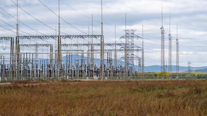 Electrical power substation and high-voltage transmission towers in a rural field, symbolizing energy distribution, infrastructure, and technology.