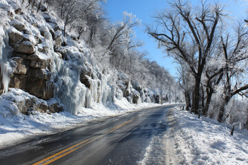 Icy winter road surrounded by frosted trees and glistening icicles, creating a serene and picturesque winter landscape with copy space