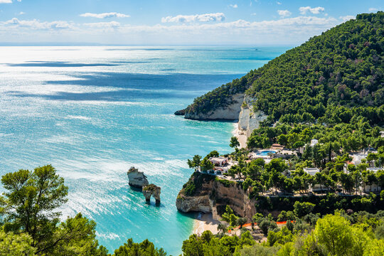 Sweeping view of the sandy shoreline and gentle waves along the beach of Baia delle Zagare, Apulia, Italy