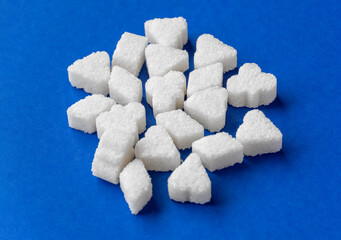 White sugar piece cubes in the form of figurines on blue background.