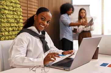Confident African American businesswoman smiling at desk in modern office
