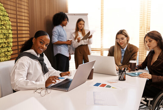 Inclusive team working at office table, woman in wheelchair using digital tablet