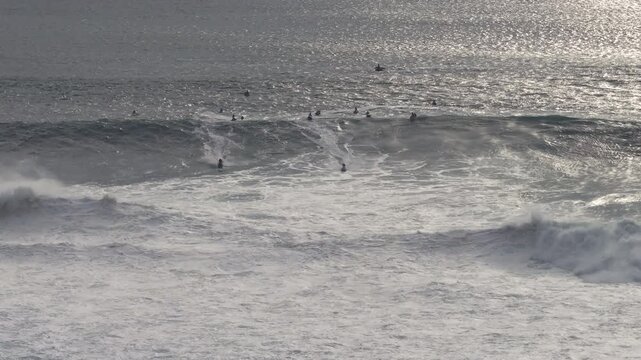 Aerial view of jet ski riders and surfers celebrating in the ocean after the extreme big wave surfing event at Nazare, Portugal