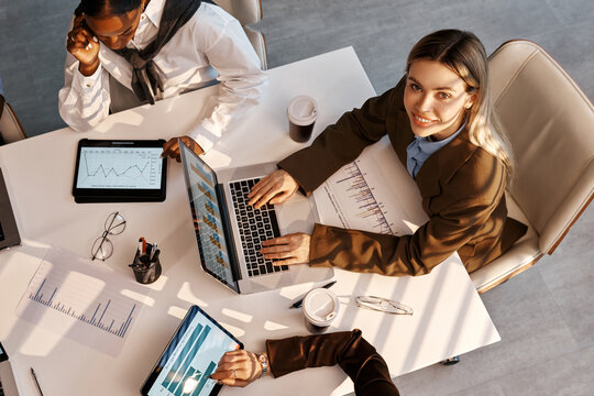 Diverse business team analyzing charts during office meeting from top view