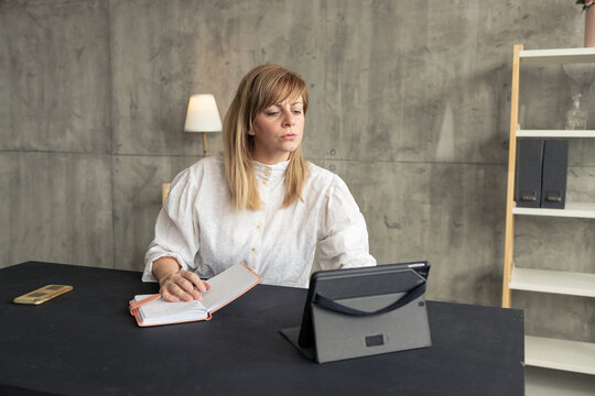 Businesswoman working from home office using tablet and taking notes on notebook