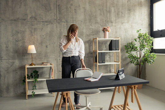 Businesswoman talking on phone in modern industrial office - Powered by Adobe