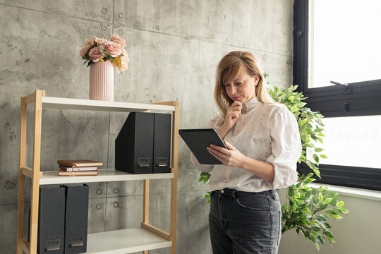 Businesswoman reading information on tablet and thinking in modern office - Powered by Adobe