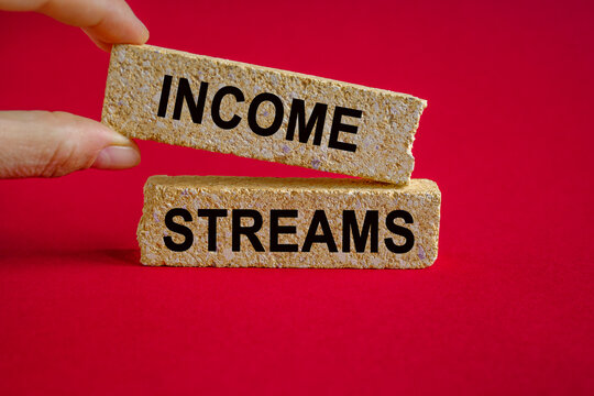 Income streams symbol. Brick blocks with the inscription - Income streams. Beautiful red background. Businessman hand. Business and finance concept.