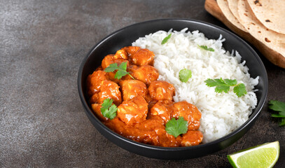 Traditional indian Butter chicken with basmati rice, cilantro and roti on a gray background. Banner.