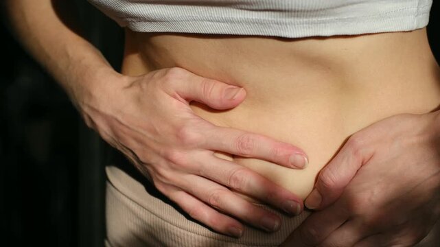 Young woman hands pressing on her abdomen, showing symptoms of severe stomachache, menstrual cramps, bloating, or food poisoning, representing digestive health problems and discomfort