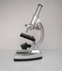 Metal microscope on a light background, side view, single object, subject shooting. A baby microscope on a white background.