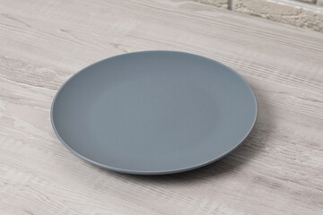 Simple gray plate resting on a wooden table in a modern kitchen setting