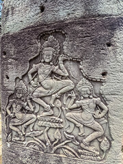 An intricate and well-preserved bas-relief carving shows celestial Apsara dancers in motion on a weathered stone wall, showcasing ancient Khmer artistry at a temple in Siem Reap, Cambodia.