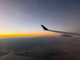 Fototapeta premium Airplane Wing Over Sunset Skyline and Glowing Horizon