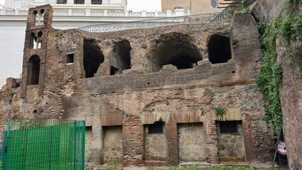 Rome, Italy - 11 January 2025. The Ara Coeli Insula displays layered brickwork, arched voids, and gridded windows with a green barrier and vines climbing the side wall near the Capitoline Hill. © Michael