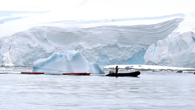 An expedition guide tows kayaks with a zodiak boat in preparation for an excursion with tourists.