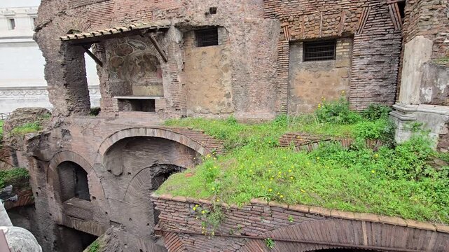 Rome, Italy - 11 January 2025. A green patch covers ancient brick vaults over shadowed chambers at Ara Coeli Insula, framed by eroded stone walls and barred window openings.